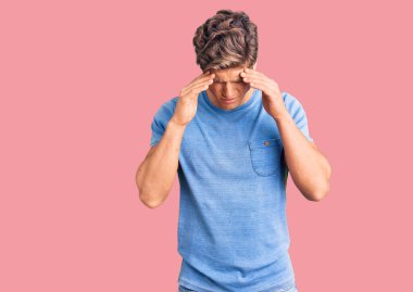 Stres yüzünden başı ağrıyan, sıradan kıyafetler giyen genç ve yakışıklı bir adam. migren ağrısı. 