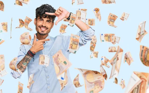 Gündelik kıyafetler giyen, gülümseyen, elleri ve parmakları gülen yüzlü, çerçeveli bir İspanyol. yaratıcılık ve fotoğrafçılık kavramı.