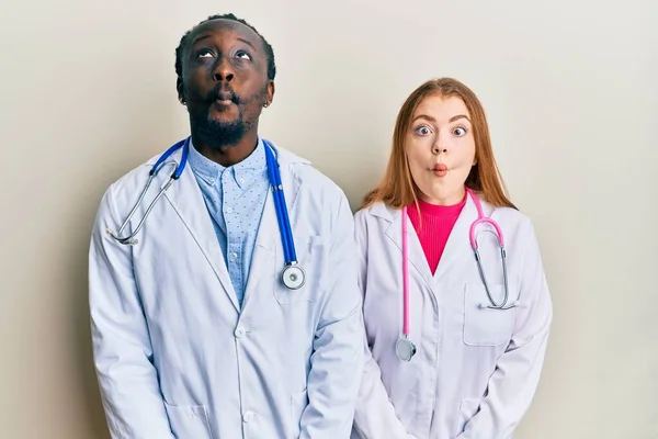 Joven Pareja Interracial Vistiendo Uniforme Médico Estetoscopio Haciendo Cara Pez —  Fotos de Stock