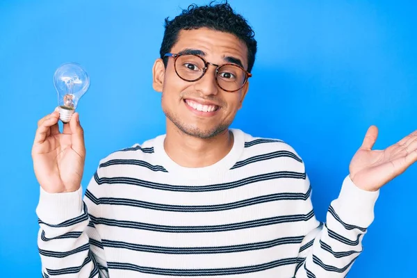 Young Handsome Hispanic Man Holding Lightbulb Inspiration Idea Celebrating Achievement — Stock Photo, Image