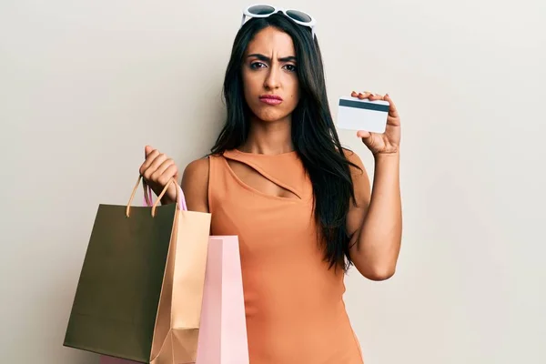 Schöne Hispanische Frau Mit Einkaufstaschen Und Kreditkarte Skeptisch Und Nervös — Stockfoto