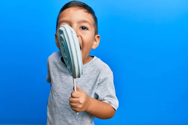 Adorable Niño Latino Comiendo Deliciosa Piruleta Sobre Fondo Azul Aislado — Foto de Stock