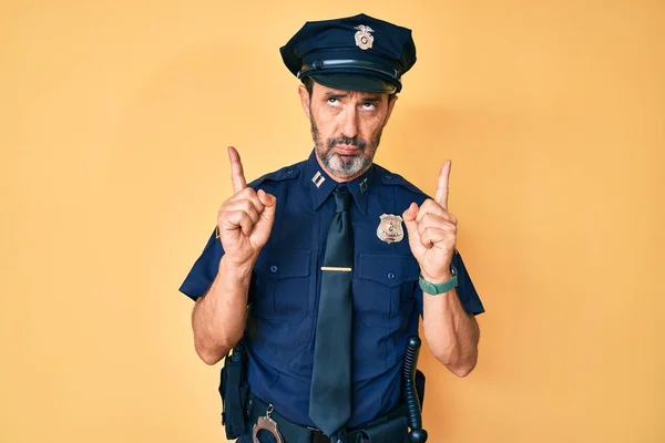 Middle age hispanic man wearing police uniform pointing up looking sad and upset, indicating direction with fingers, unhappy and depressed.