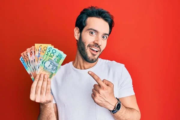 Ung Latinamerikan Man Håller Australiska Dollar Ler Glad Pekar Med — Stockfoto