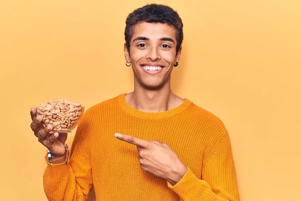 Young African Amercian Man Holding Peanuts Smiling Happy Pointing Hand — Stock Photo, Image