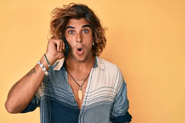 Genç İspanyol bir adam akıllı telefondan konuşuyor. Korkmuş ve şaşırmış bir şekilde ağzı açık, inançsız bir yüz. 