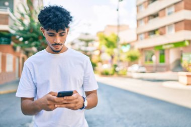 Şehirde akıllı telefon kullanan, ciddi bir suratı olan genç bir Arap..