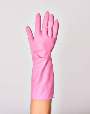 Pembe temizleme eldiveni giymiş beyaz arka planda el sıkışma işareti yapan beyaz bir kadının eli.