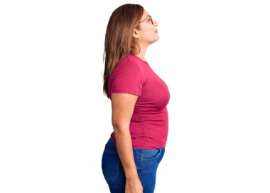 Orta yaşlı, sıradan kıyafetler ve gözlük takan Latin bir kadın, rahat bir profil pozu, kendine güvenen bir gülümsemesi olan doğal bir poz.. 