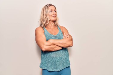 Orta yaşlı, beyaz, spor giysili, kolları çapraz ve kendinden emin bir kadın. 