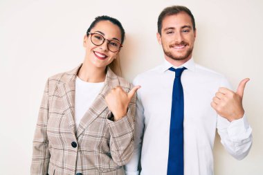 Güzel bir çift iş kıyafetleri giyip arka tarafı gösteriyorlar. Elleri havada, gülümsüyorlar. 