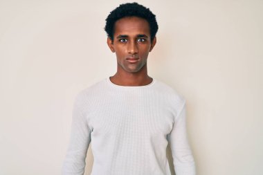 Yüzünde ciddi bir ifade olan sıradan bir kazak giyen Afrikalı yakışıklı bir adam. Basit ve doğal bir şekilde kameraya bakıyorsun.. 