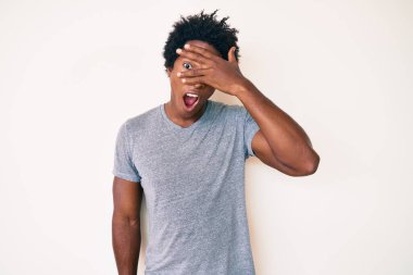 Yakışıklı Afro saçlı, sıradan kıyafetler giyen, yüzünü ve gözlerini elleriyle kapatan, parmaklarından korkan Afro-Amerikan erkeği. 