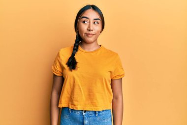 Gündelik kıyafetler giyen genç Latin kadın gülümseyip yan tarafa bakıyor ve düşünüyor.. 