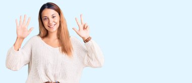 Güzel, genç bir kadın gündelik giysiler giyer ve sekiz numaralı parmaklarıyla işaret ederken kendinden emin ve mutlu gülümserdi.. 