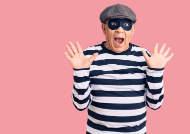 Hırsız maskesi ve tişört giyen kıdemli yakışıklı adam çılgınlığı kutluyor ve kolları açık ve gözleri açık heyecanla haykırarak başarıdan hayrete düşüyor. Kazanan konsept 