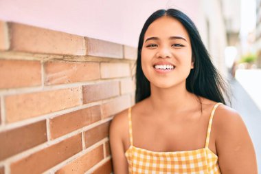 Genç Asyalı kız şehirde mutlu bir şekilde gülümsüyor.