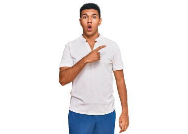 Gündelik giysiler giyen genç bir Arap, parmaklarını yana doğru göstererek şaşırdı, ağzı açık hayret içinde kaldı.. 