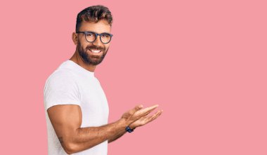 Gündelik kıyafetler ve gözlük takan genç İspanyol adam avuçlarını açıp fotokopi alanını gösteriyor, gülümseyerek mutlu bir gülümseme sergiliyor. 