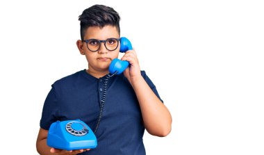 Küçük çocuk klasik telefon kullanma tavrı ve ayık yüz ifadesi kullanıyor. Kendine güveniyor gibi görünüyor. 