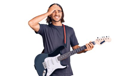 Elektro gitar çalan genç yakışıklı adam gergin ve hayal kırıklığına uğramış, şaşırmış ve kızgın yüzlü. 