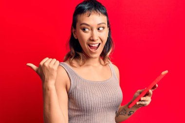 Dokunmatik tablet tutan genç bir kadın başparmağını yana doğru uzatıyor ve ağzı açık gülümsüyor. 