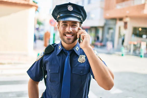 年轻英俊的惊慌失措的警察穿着警服开心地笑着 站在街上 面带微笑地聊天 用智能手机聊天 — 图库照片