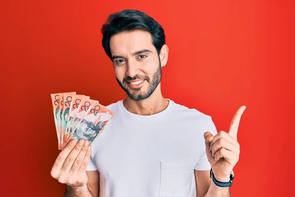 Ung Latinamerikan Man Håller Australiska Dollar Ler Glad Pekar Med — Stockfoto