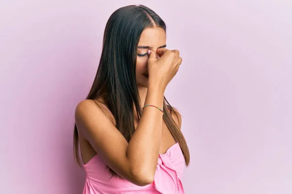 Young hispanic woman wearing casual style with sleeveless shirt tired rubbing nose and eyes feeling fatigue and headache. stress and frustration concept.