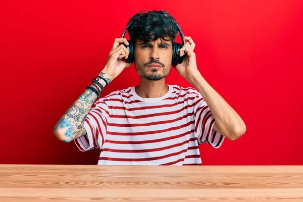 Junger Hispanischer Mann Mit Kopfhörern Sitzt Skeptisch Und Nervös Auf — Stockfoto