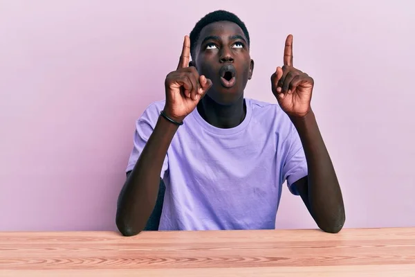 Jovem Afro Americano Vestindo Roupas Casuais Sentado Mesa Espantado Surpreso — Fotografia de Stock