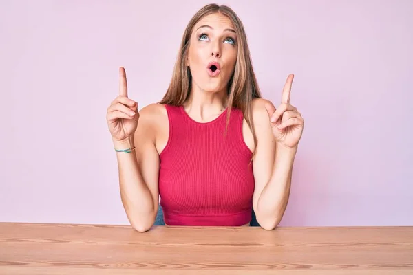 Jong Blond Meisje Dragen Casual Kleding Zitten Tafel Verbaasd Verrast — Stockfoto