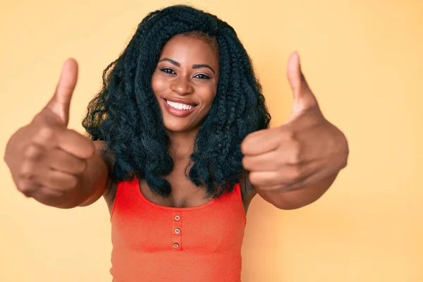 手で積極的なジェスチャーを行うことを承認カジュアル服を着て美しいアフリカの女性 親指アップ笑顔と成功のために幸せ 勝者のジェスチャー — ストック写真