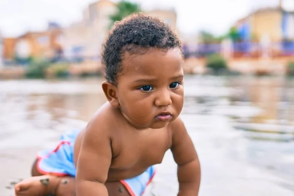 愛らしいアフリカ系アメリカ人の幼児がビーチに座っています — ストック写真