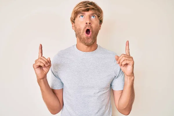 Young Blond Man Wearing Casual Clothes Amazed Surprised Looking Pointing — Stock Photo, Image