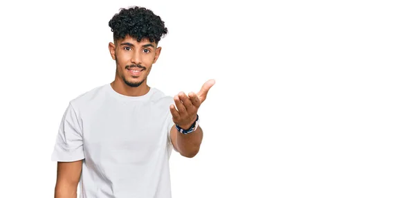 Hombre Árabe Joven Vistiendo Camiseta Blanca Casual Sonriendo Amistoso Ofreciendo —  Fotos de Stock