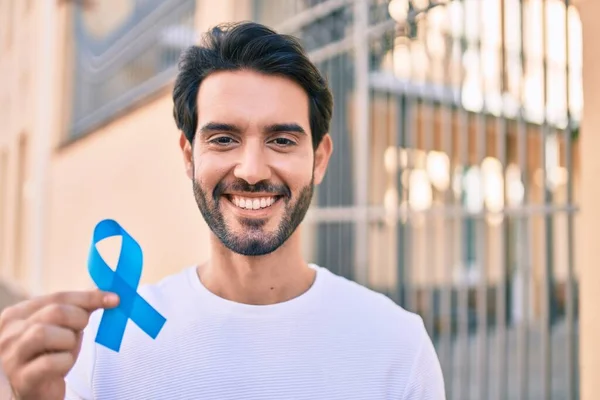 Joven Hombre Hispano Sonriendo Feliz Sosteniendo Cinta Azul Ciudad — Foto de Stock
