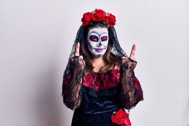 Young woman wearing day of the dead costume over white showing middle finger doing fuck you bad expression, provocation and rude attitude. screaming excited 