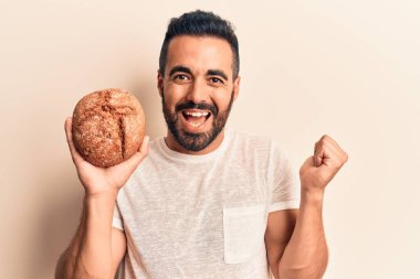 Genç İspanyol adam ekmek tutuyor gururla bağırıyor, zaferi kutluyor ve başarıyı kollarını kaldırarak kutluyor. 