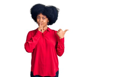 Gündelik giysiler giymiş genç Afro-Amerikalı kız sessiz olmak istiyor. Parmakları dudaklarında, elleri yandan işaret ederek. sessizlik ve gizli konsept. 