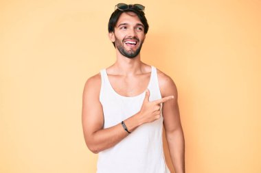Yaz görünüşü ve güneş gözlüğü takan yakışıklı İspanyol bir adam. Yüzünde mutlu ve doğal bir ifadeyle elleri ve parmaklarıyla yüzünü gösteren bir gülümseme. 