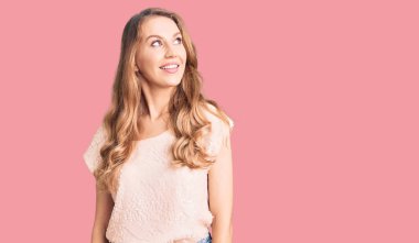 Sarı saçlı, sıradan kıyafetler giyen, gülümseyen ve kafasını çeviren güzel beyaz bir kadın.. 