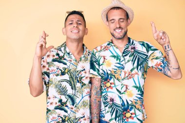 Yaz şapkası takan ve Hawaii gömleği giyen iki genç eşcinsel umut ve gözleri kapalı gülümseyerek el sallıyor. Şans ve batıl inançlar. 