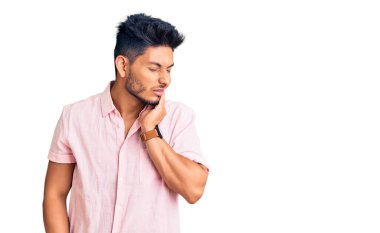 Yakışıklı Latin Amerikalı sıradan bir yaz tişörtü giymiş diş ağrısı ya da diş hastalığından dolayı ağızlarına acı dolu bir ifadeyle dokunuyor. dişçi 