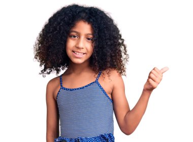 Kıvırcık saçlı, mayo giyen, gülümseyen, gülümseyen ve baş parmağıyla yüzünü gösteren Afro-Amerikan çocuğu.. 
