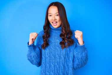 Sıradan bir kazak giyen genç, güzel Çinli kız kollarını kaldırıp, gözlerini açarak başarının şaşkınlığını ve şaşkınlığını yaşıyor. Kazanan konsept. 