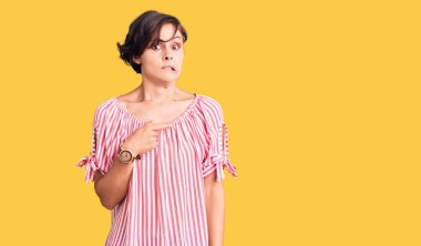 Kısa saçlı, rahat yaz kıyafetleri giyen güzel bir kadın endişeli ve endişeli bir ifade takınıyor. 