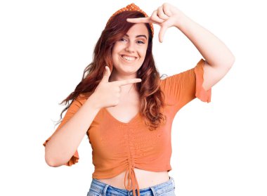 Gündelik kıyafetler giyen, gülümseyen, elleri ve parmakları gülen yüzlü genç ve güzel bir kadın. yaratıcılık ve fotoğrafçılık kavramı. 