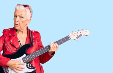 Son sınıf güzeli, mavi gözlü, gri saçlı, modern görünümlü, şok olmuş yüzüne elektro gitar çalan, şüpheci ve alaycı görünen, ağzı açık bir şekilde şaşırmış bir kadın. 