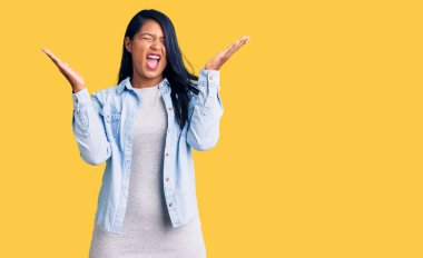 Uzun saçlı İspanyol kadın, sıradan bir kot ceket giyip başarının çılgınlığını kutluyor. Kolları havada, gözleri kapalı, heyecanla bağırıyor. Kazanan konsept 